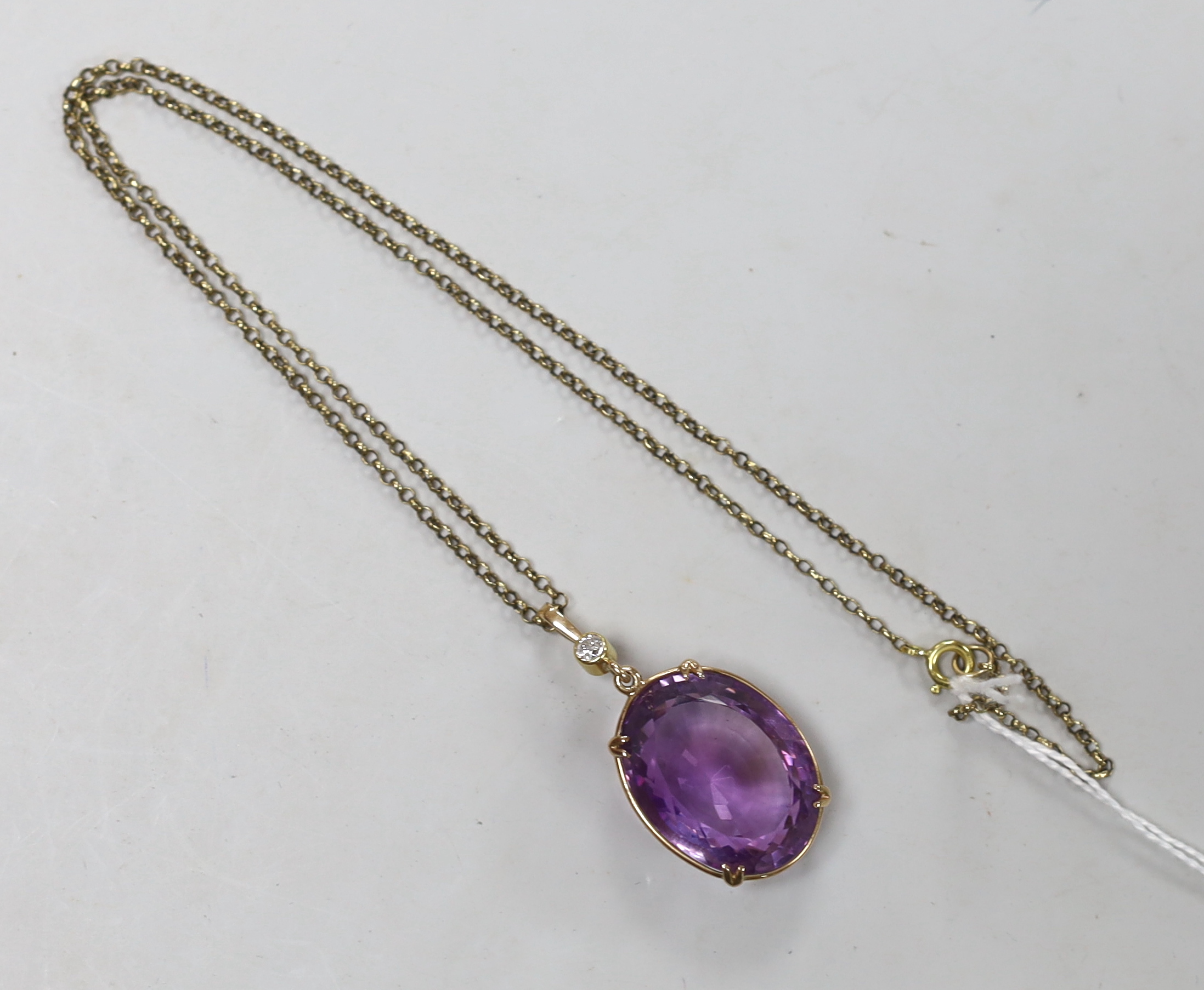 An early 20th century 15ct and single stone oval cut amethyst set pendant, with single stone diamond set bale, overall 42mm, on a gold plated chain.
